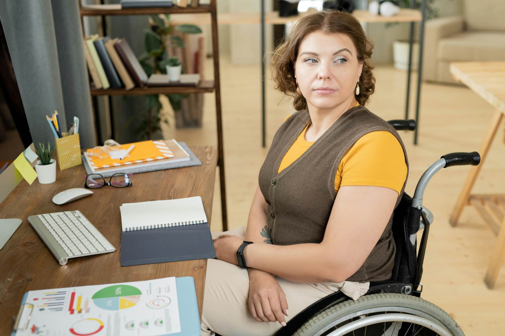 donna con disabilità motoria siede al tavolo davanti alla tastiera di un pc